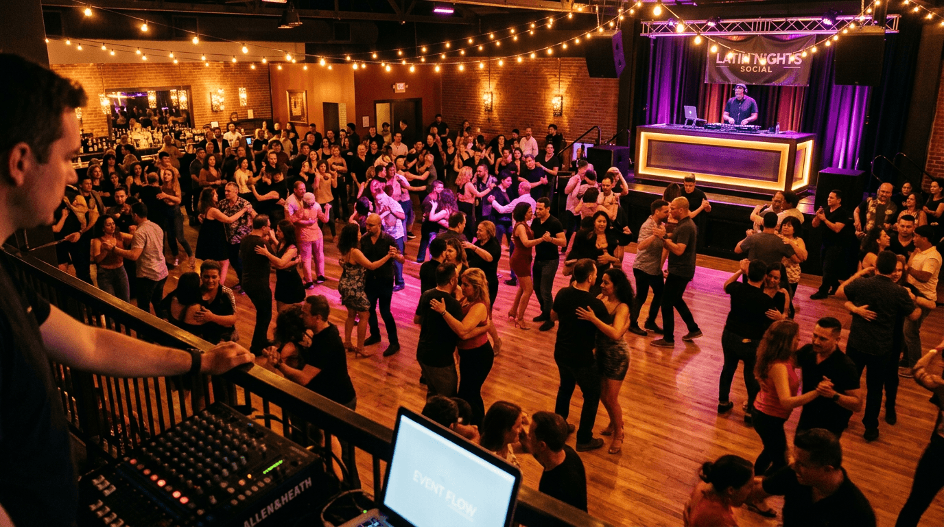 A packed Latin dance social with couples dancing bachata and salsa under warm lights